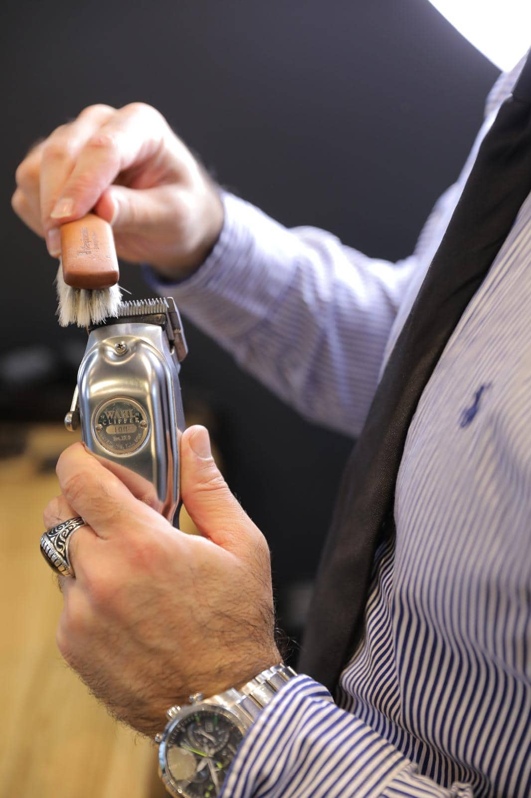 H&auml;nde reinigen eine Wahl-Haarschneidemaschine mit einer B&uuml;rste